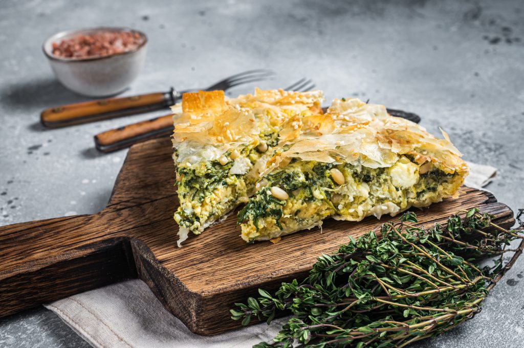 Greek Pie Spanakopita with Spinach and Cheese on wooden board.