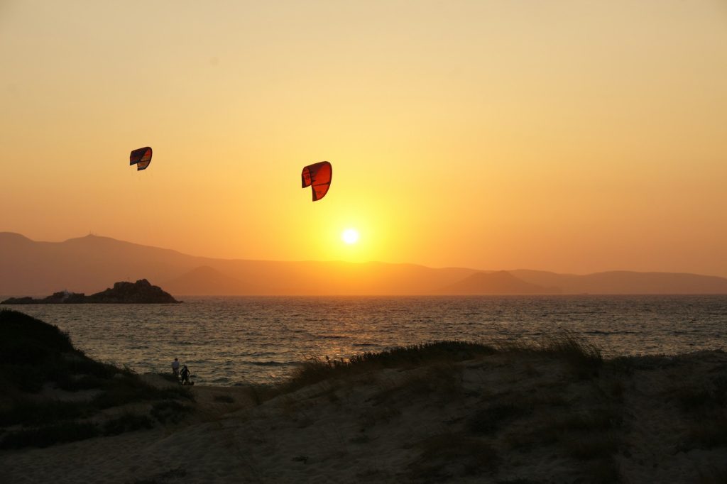 People enjoy kite surfing during the sunset in Naxos.