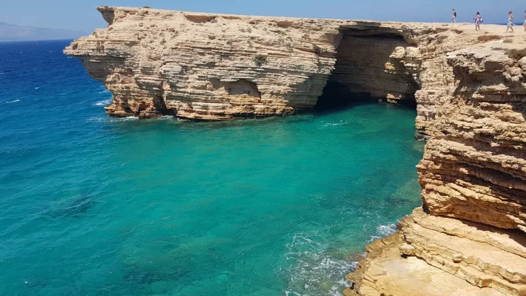 Few people standing on a great rock admiring the deep, blue sea during their koufonisia-schoinousa cruise.