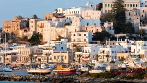 Naxos Town’s waterfront at golden hour, with fishing boats docked in the harbor and whitewashed buildings rising up the hillside.